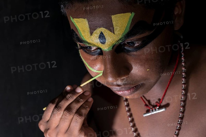 A Katakali artist is applying the make-up of the character Arjun for the Santhana Gopalam play during a temple festival