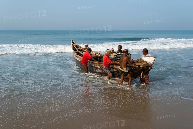 Fishermen pushing a boat onto the beach