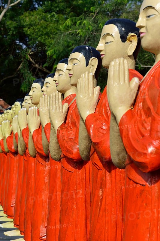 Figures of Buddhist monks in front of a monastery