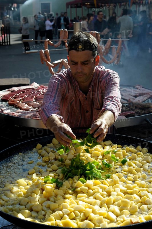 Cook adds pieces of green peppers to a large pan containing potato stew at the annual All Saints Market in Cocentaina