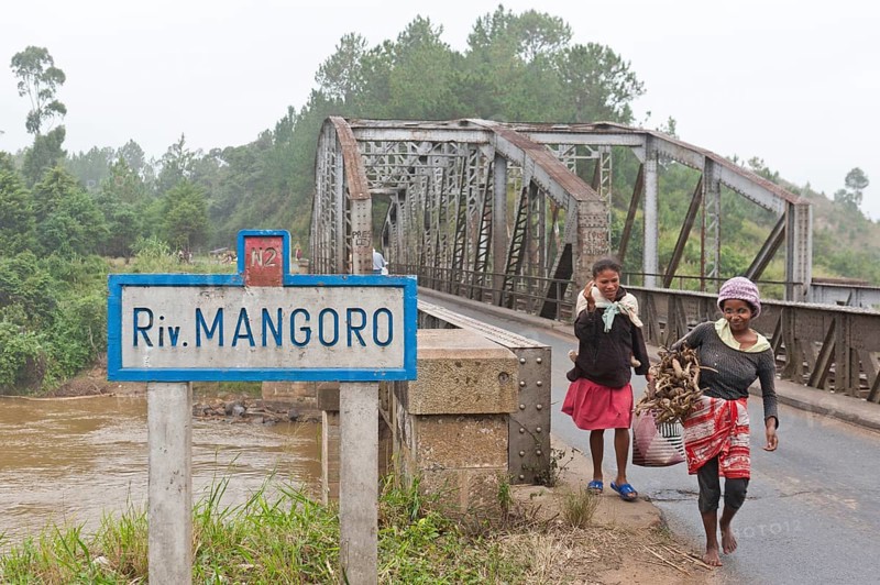 Two women crossing an old iron bridge over the Mangoro River