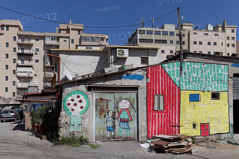 Brightly painted huts in front of modern residential buildings
