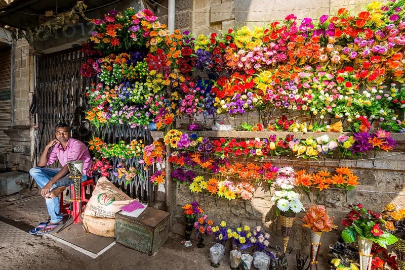 A street vendor is selling colorful artificial flowers