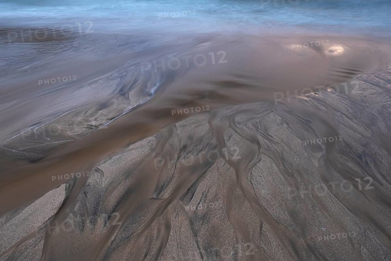 Water flows into the sea at the sandy beach