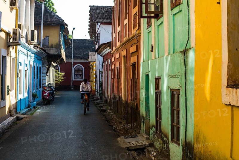 A small lane with colourful houses and a cyclist