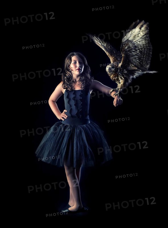 Girl wearing a black ballet dress with a bird of prey on her arm