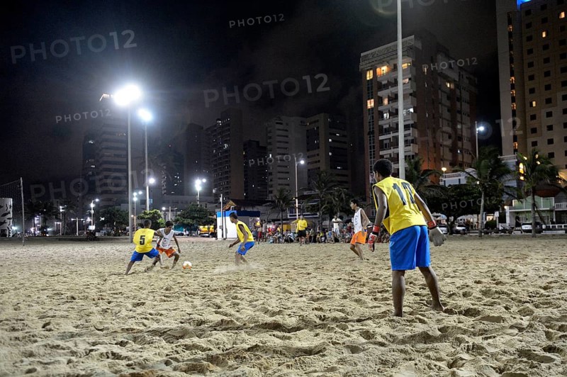 Young people playing football in the evening at the beach