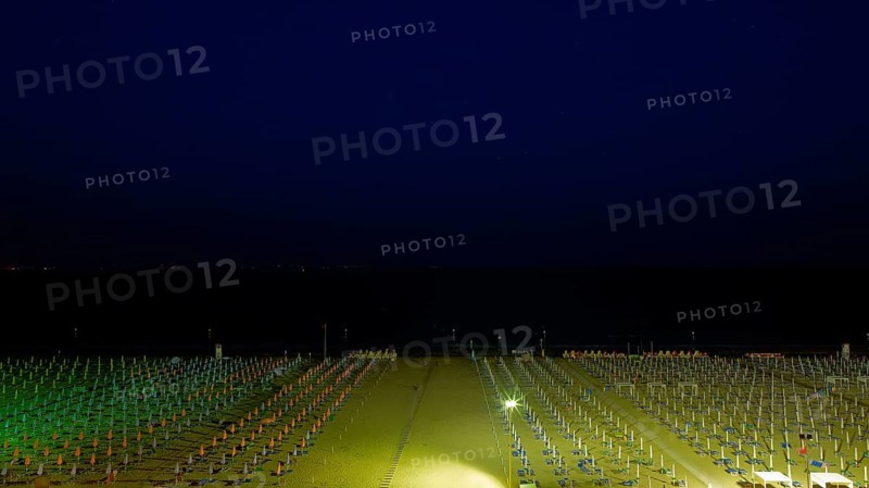 View of a beach with sunshades and sun beds at midnight
