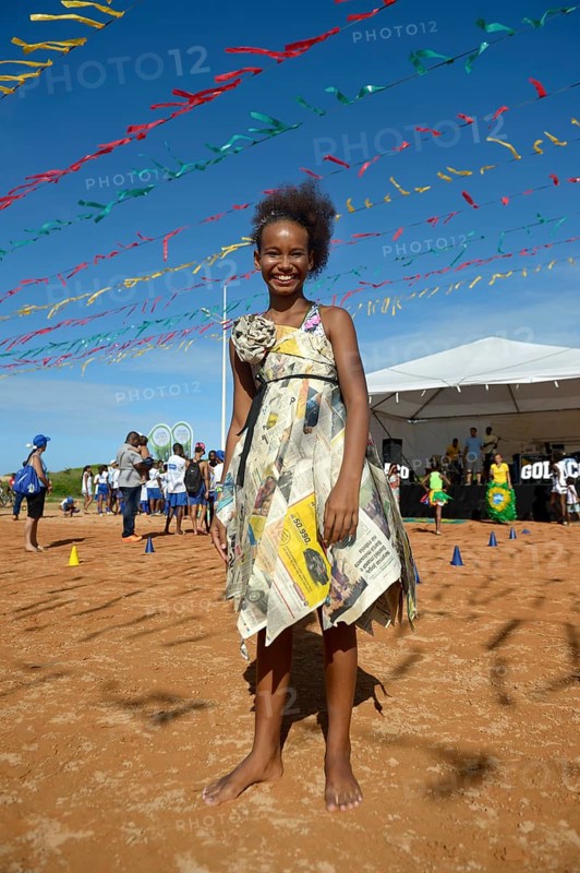 Girl presenting a dress made of recycled newspapers at a fashion show of a social project