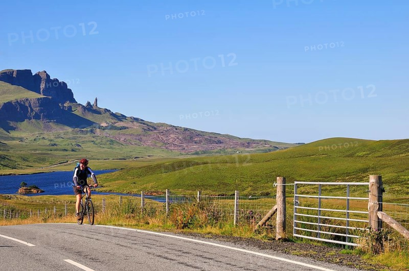 Cyclist on a road at The Storr with the The Old Man of Storr pinnacle