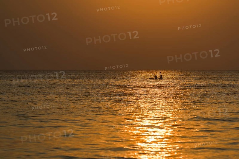 Two kayakers in the open sea at sunset