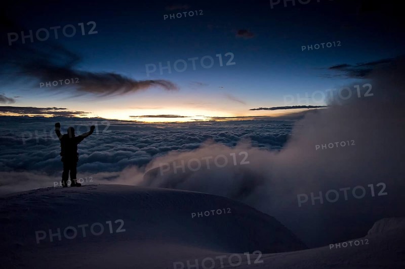 Mountain climber on the summit of Cotopaxi Volcano at sunrise