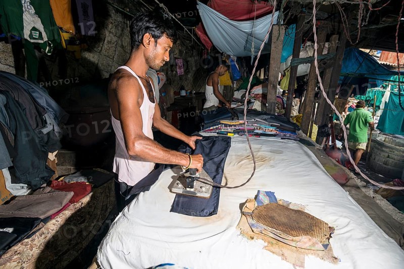 A labourer is ironing laundry at Mahalaxmi Dhobi Ghat