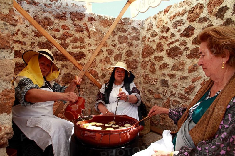Elderly women in traditional costume baking 'bunyols'