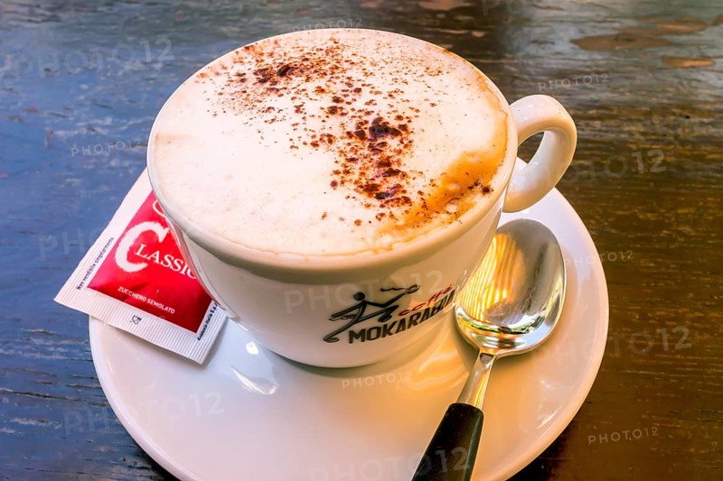 Cappuccino with a sugar sachet and a spoon