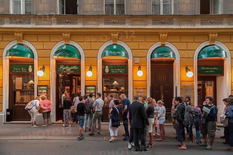 Tourists wait in long queues in front of the famous Schnitzel restaurant Figlmuller
