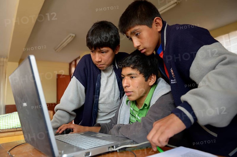 Three boys in a children's home are working together on a laptop
