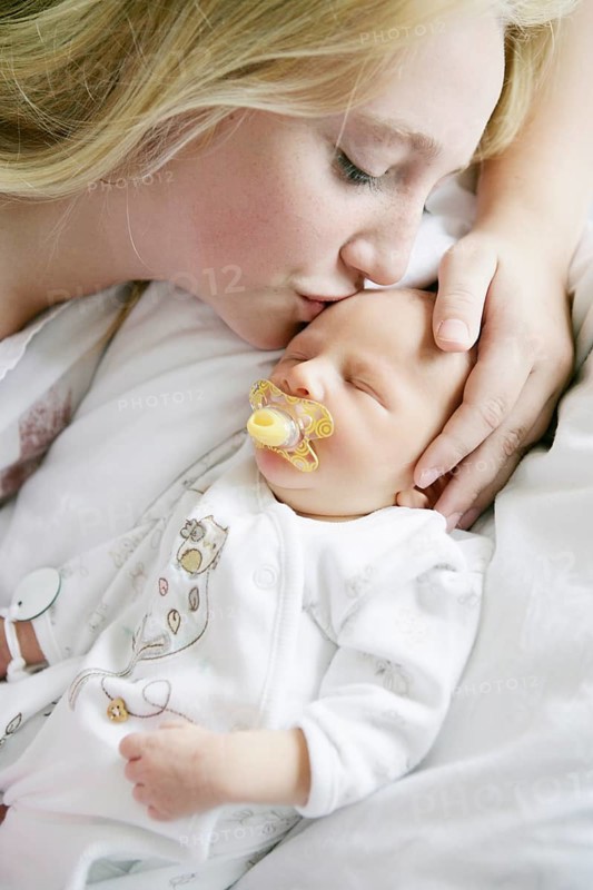 Big sister kissing her newborn brother