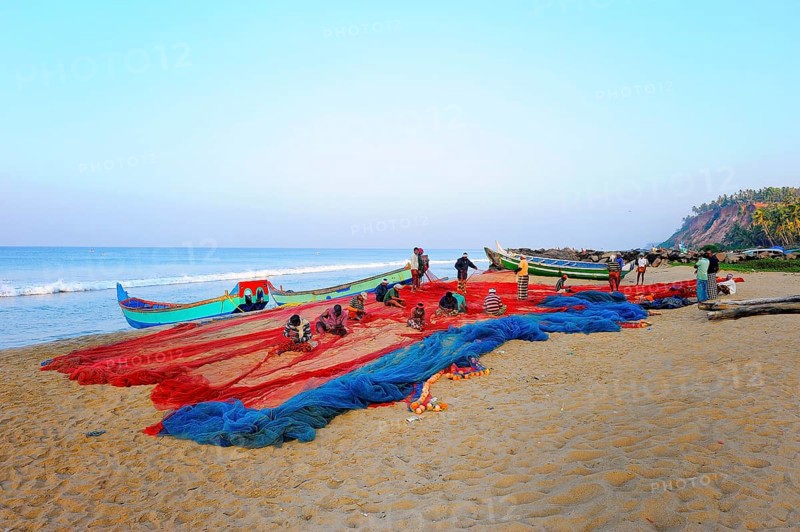 Fishermen repairing nets on the beach