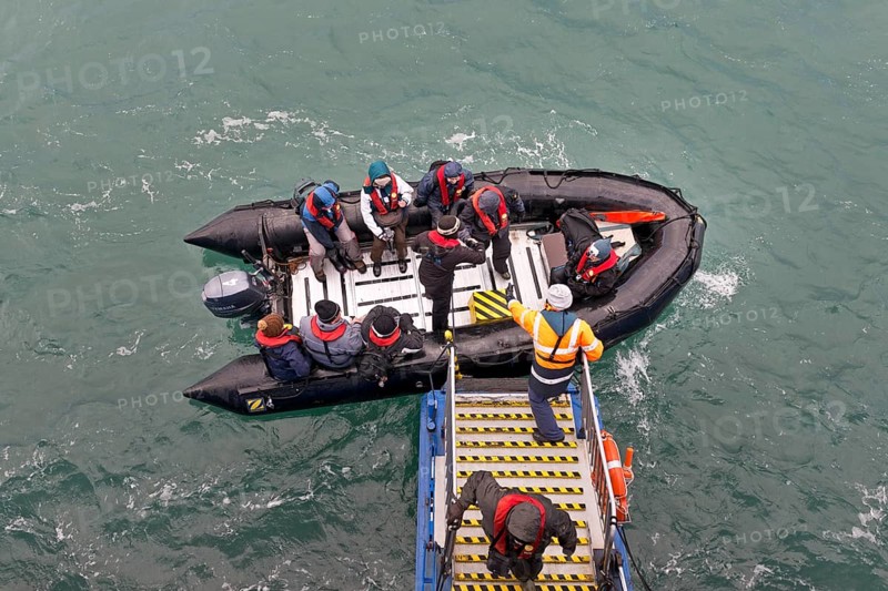 Tourists being helped out of an inflatable boat