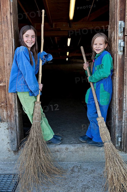 Two sisters holding stable brooms