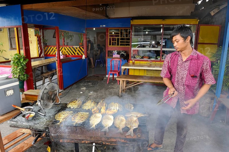 Javanese man grilling fish in a restaurant