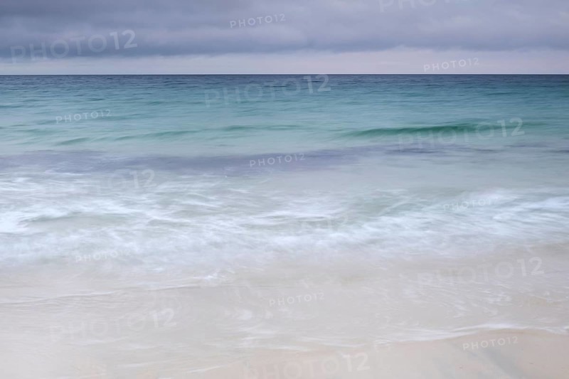 Spray and waves running on a sandy beach