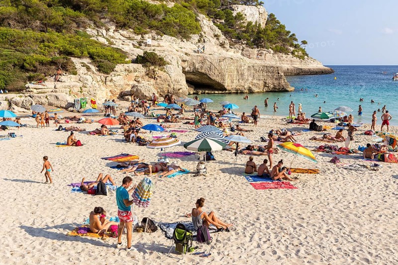 Tourists on the sandy Cala Mitjana Beach