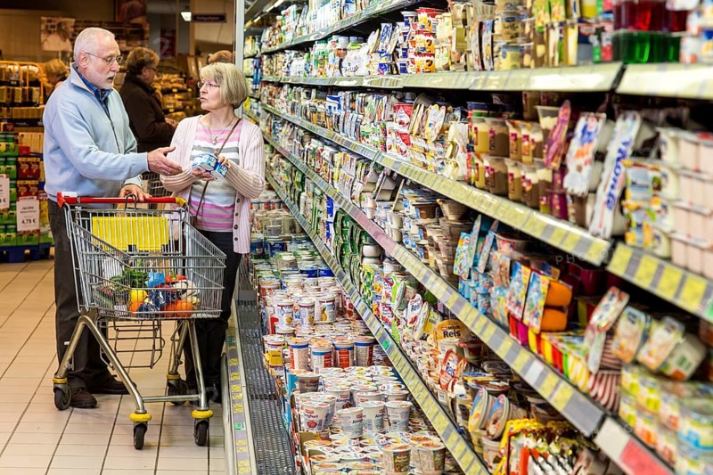 Senior couple shopping with a shopping trolley in the refrigerated dairy section in a supermarket