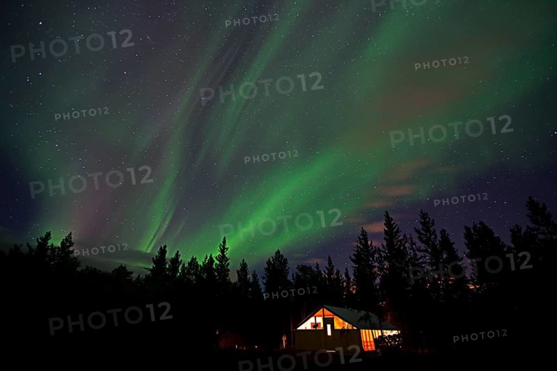 Curtains of northern polar lights and iluminated cabin