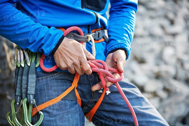 Climber attaching a figure of eight knot on his climbing rope