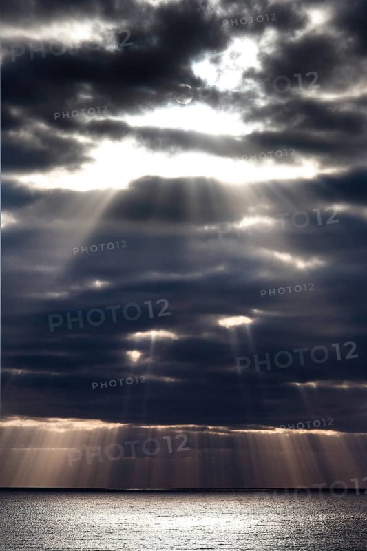 Sun rays shine through dark storm clouds