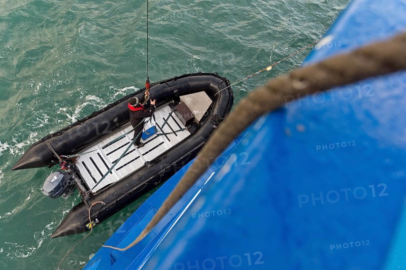 Inflatable boat being hoisted aboard an expedition ship following an excursion