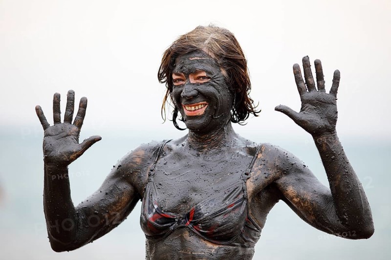 Female tourist covered in salty mud from the Dead Sea