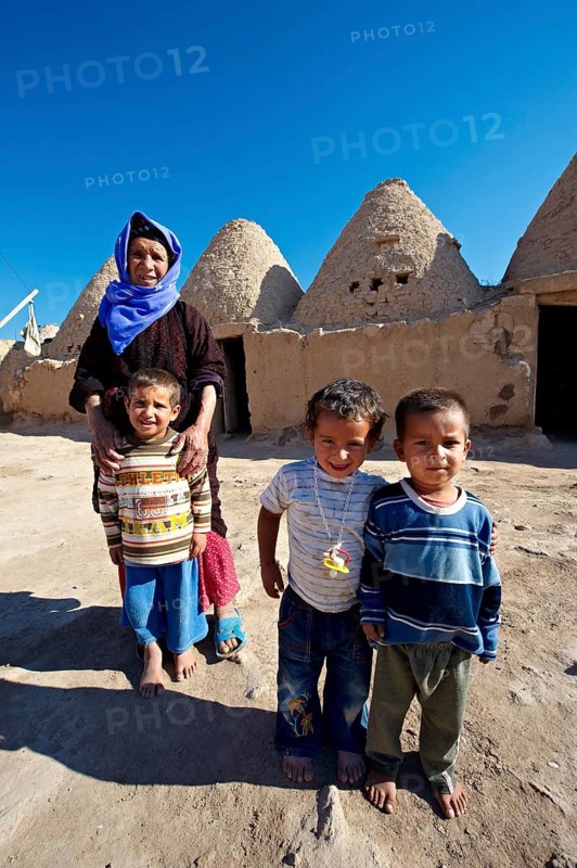 Mother and children in front of their beehive adobe buildings