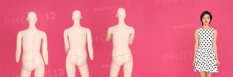 Woman standing next to a group of mannequins