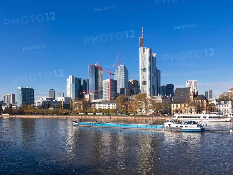 Cargo ship on the Main river in front of the skyline of Frankfurt with the buildings of Opernturm
