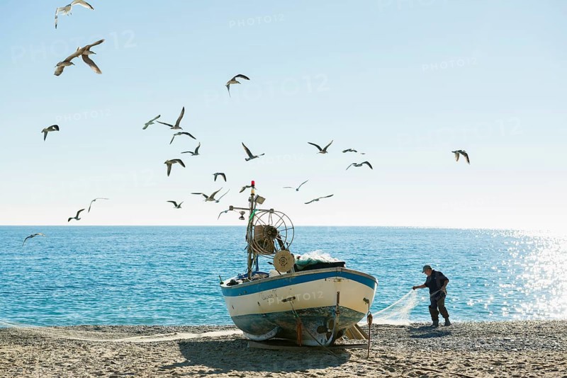 Fisherman with a fishing boat on the beach of Noli