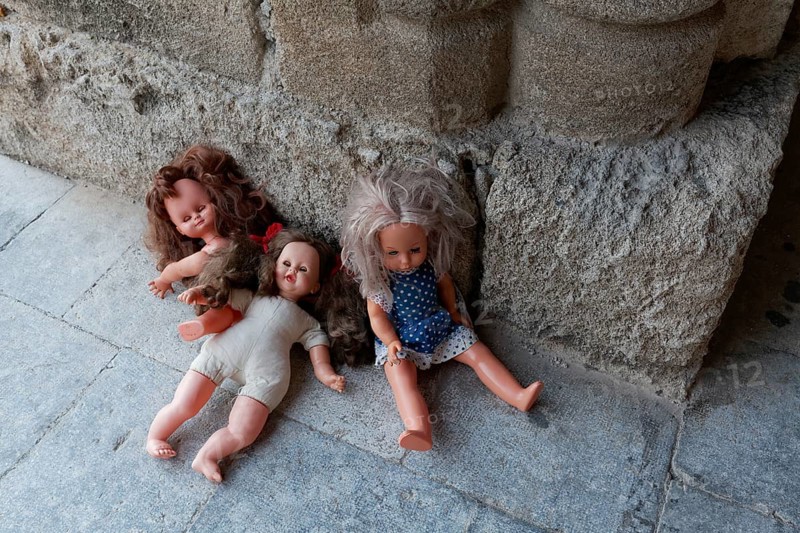 Three forgotten children's dolls beside a medieval column