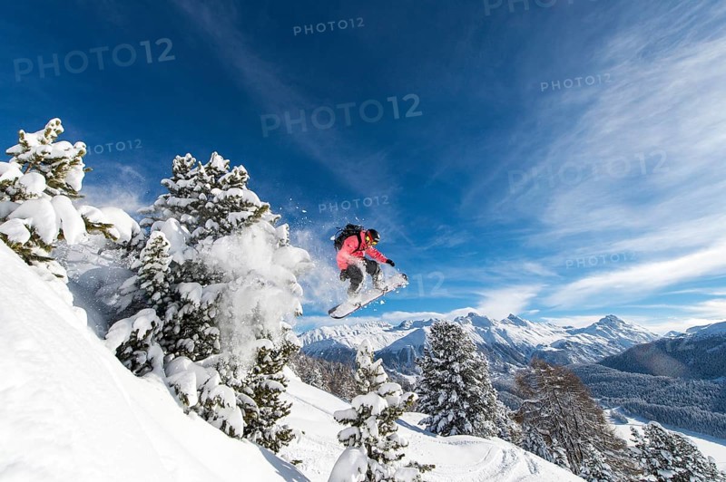 Snowboarder jumping over trees