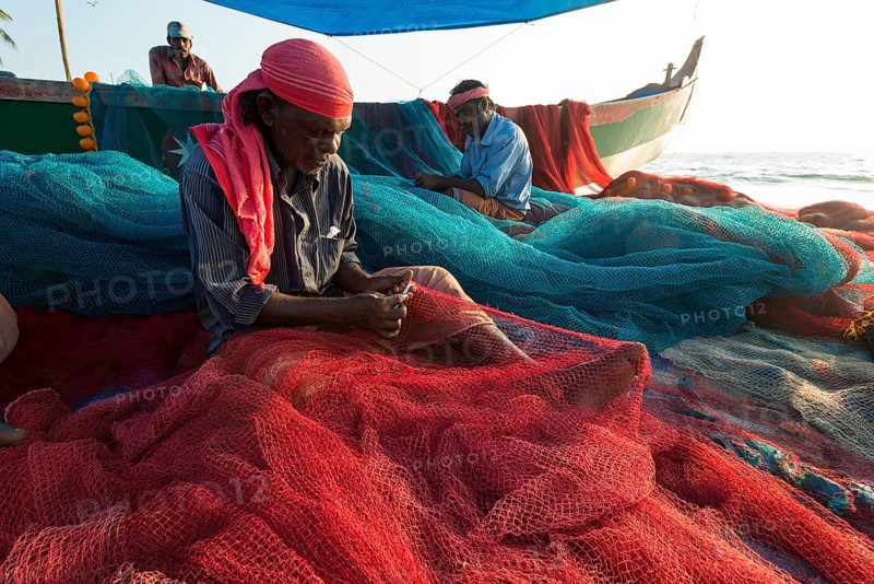 Fishermen repairing fishing nets on the beach