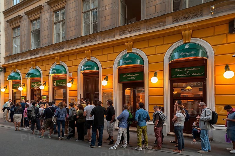 Tourists wait in long queues in front of the famous Schnitzel restaurant Figlmuller