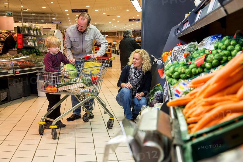 Family shopping with a shopping trolley in the fruit and vegetables department of a supermarket