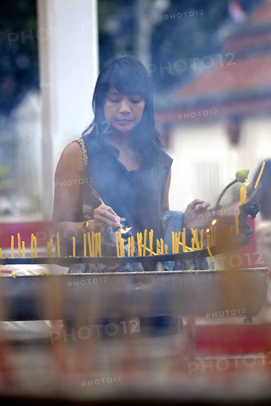Woman lighting candles outside the Wat Phra Si Rattana Mahathat Temple