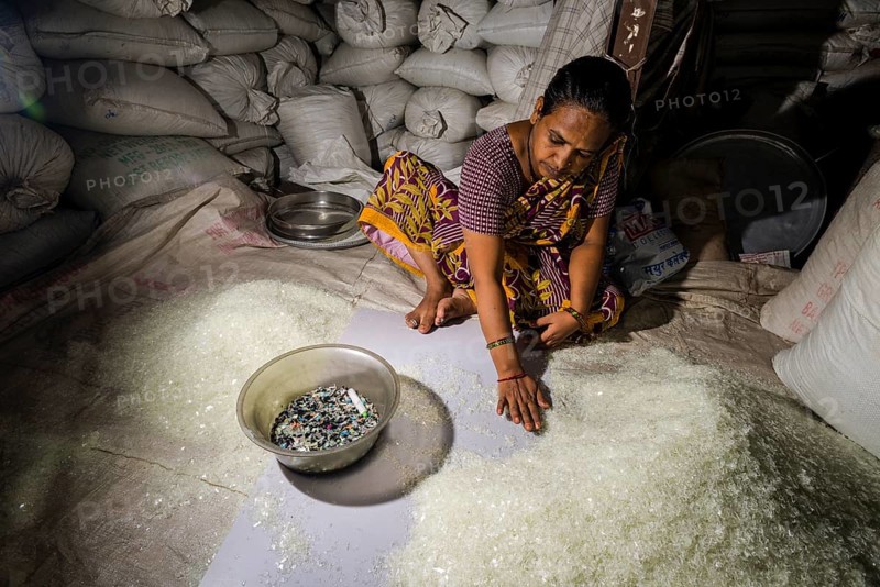 Woman sorting out shredded white plastic garbage for recycling