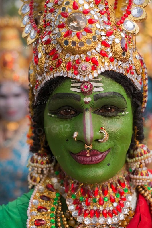 Hindu temple dancer wearing gold jewelry with his face painted green