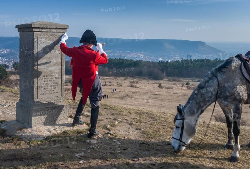 Napoleon with a telescope and horse next to his monument