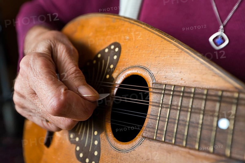Hand of an elderly woman playing a mandolin