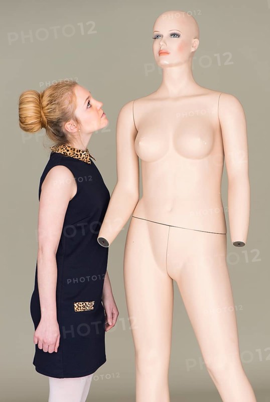 Young woman looking at naked female mannequin