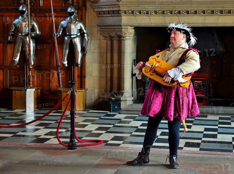 Musician in period costume performing on a medieval hurdy-gurdy
